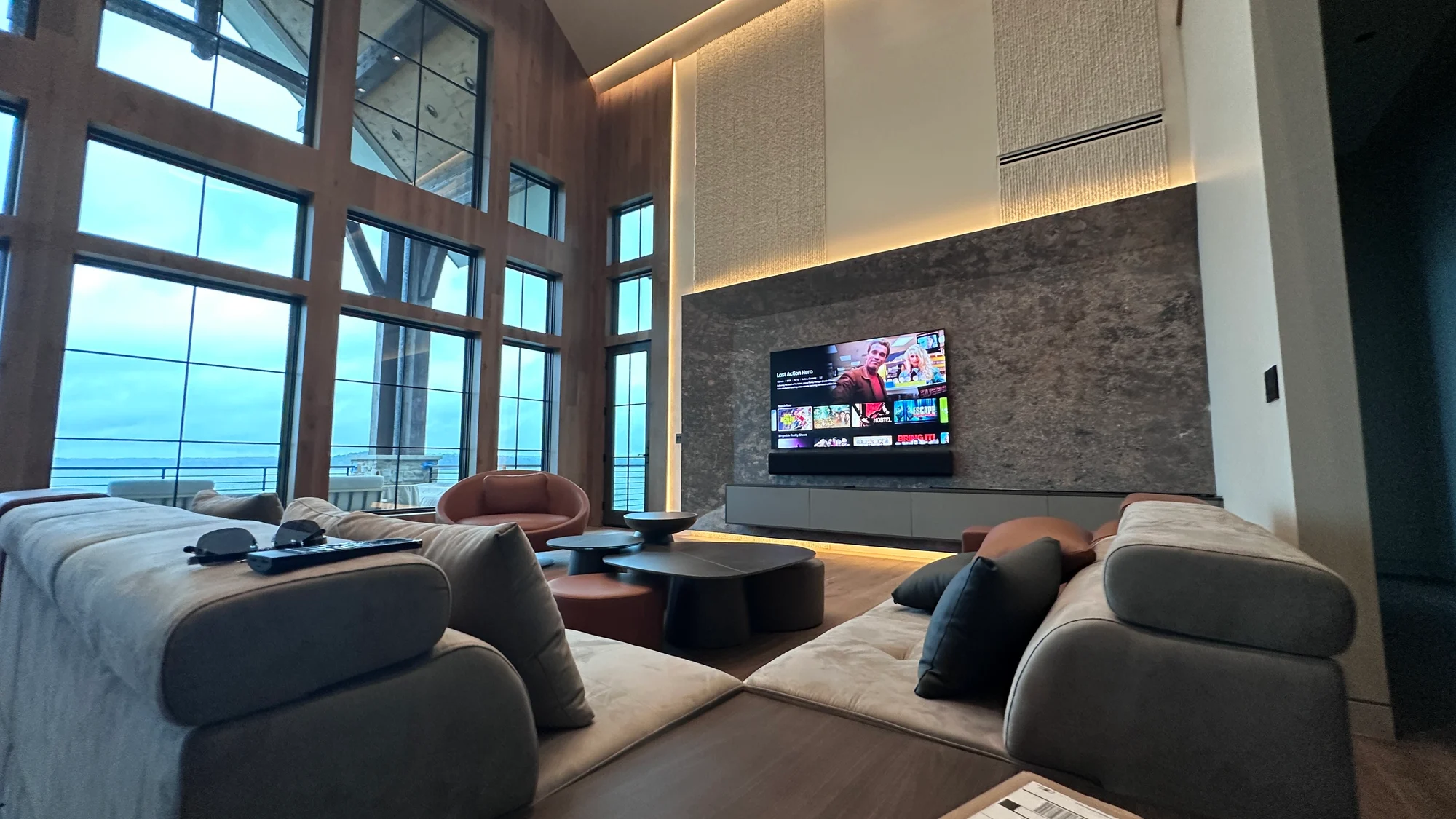 Living room with a wall-mounted display and soundbar integrated into a stone feature wall