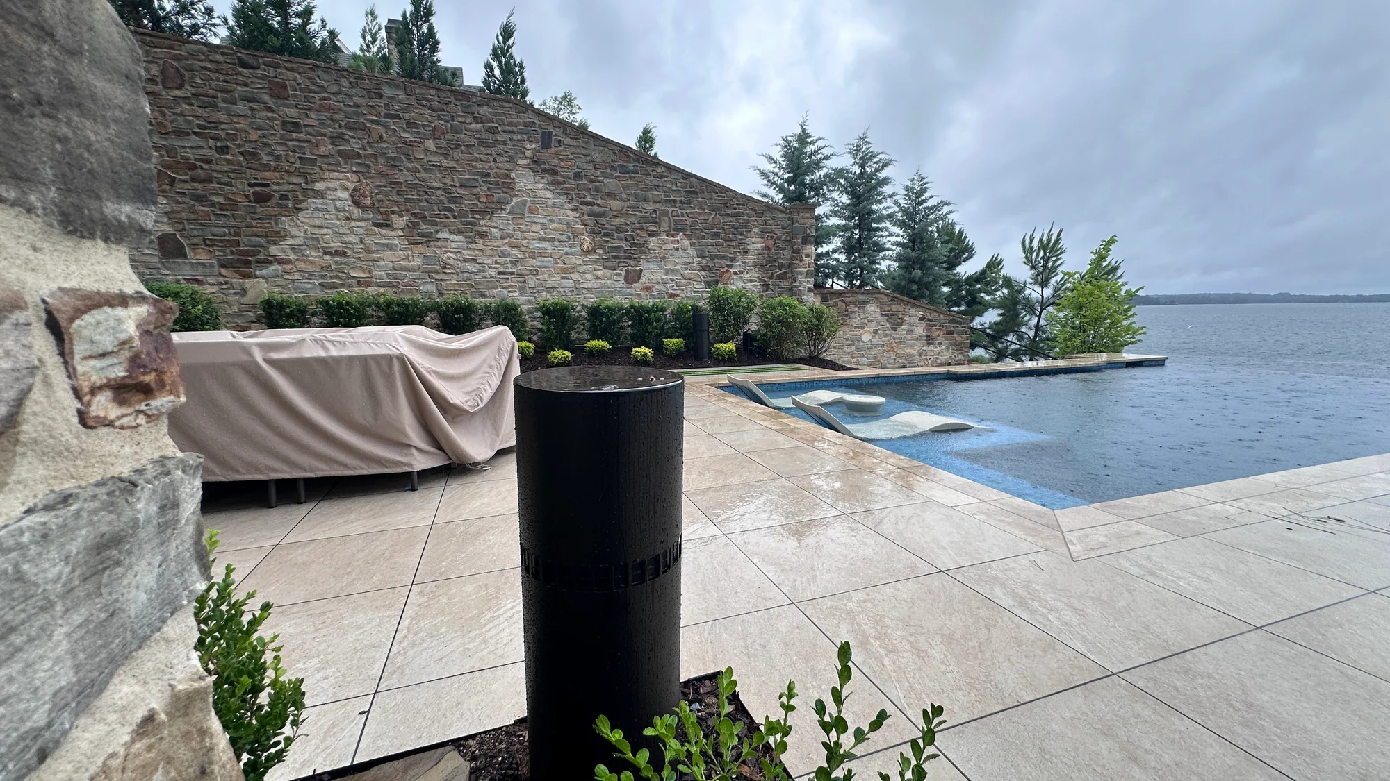 Outdoor audio installation beside a pool and landscaped stone terrace