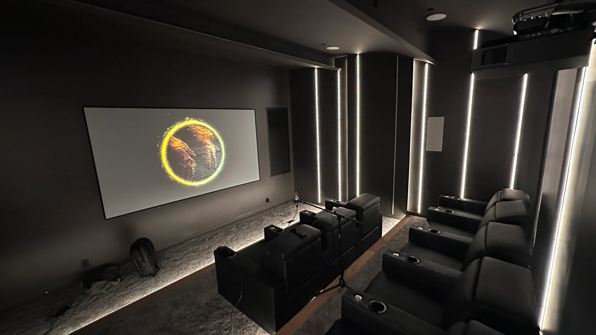 Dedicated theater with projection screen, two rows of recliners, and vertical wall lighting